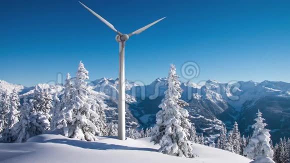 旋转风力涡轮机在阳光明媚的雪山上4K镜头视频的预览图