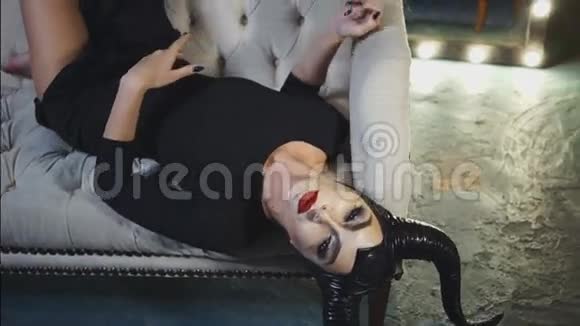 一张白色的沙发上躺着一个美丽的女孩她的形象是Maleficent黑色的大角穿着黑色的连衣裙视频的预览图