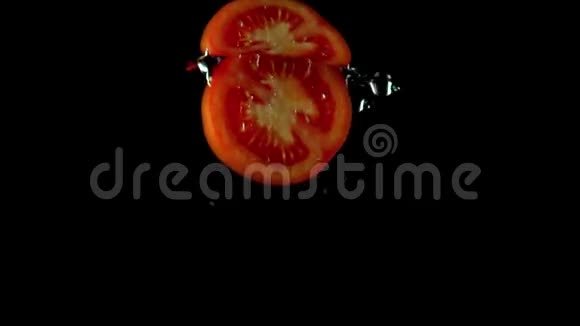 一半的红番茄落在水下超慢动作镜头下黑色背景视频的预览图