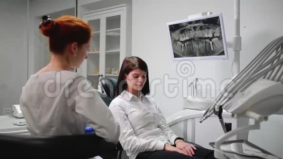 美丽的女孩在他办公室的一个牙科医生的球上疼痛指向她的牙齿白色无菌视频的预览图