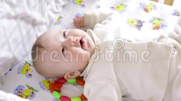 在自己的小床上醒来时一个刚出生的小男孩微笑着打喷嚏和伸展身体视频的预览图