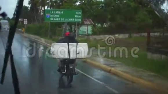当地居民在雨中骑着一辆大箱子的自行车视频的预览图