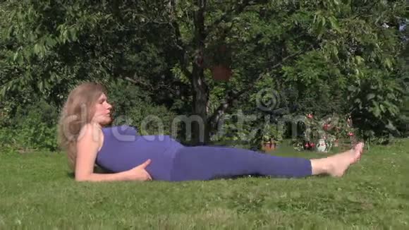 怀孕的女孩让锻炼腿躺在草地上产前运动视频的预览图