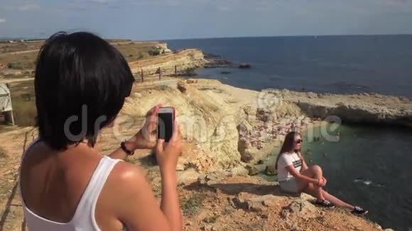 幸福的女人用智能手机在海底灯塔拍照朋友视频的预览图