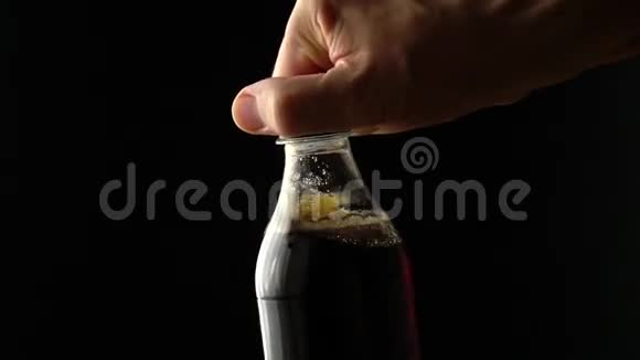 男人打开可乐塑料瓶与顶部慢镜头黑色背景视频的预览图