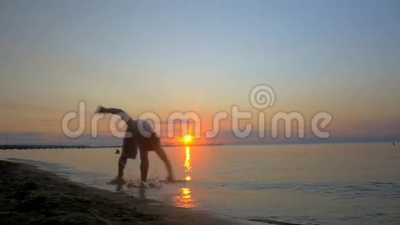 运动员在日落时在海滩上表演杂技视频的预览图