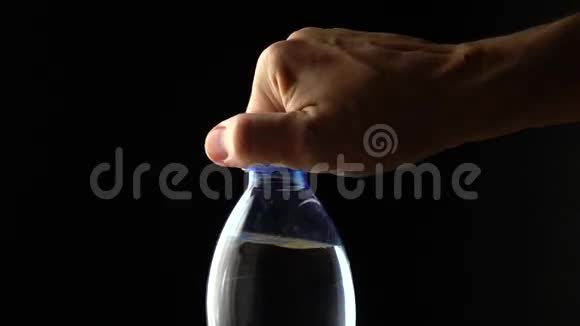 人打开塑料瓶的碳酸水黑色背景慢镜头视频的预览图