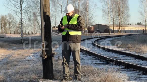 冬天工人们在铁路附近的高压电线杆上谈论智能手机视频的预览图