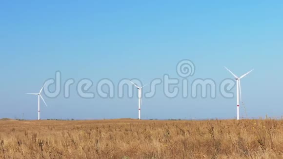 麦田的风力涡轮机蓝天背景下麦田旋转风力涡轮机组视频的预览图