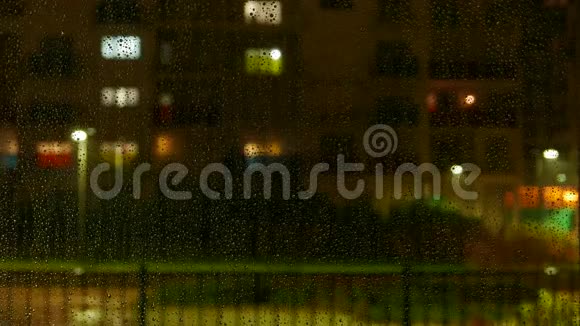 外面下雨时窗户上有水滴离焦的多层建筑背景有窗户照明和活动视频的预览图