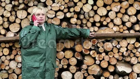 穿着绿色光滑衣服的女人站在木材旁边在打电话视频的预览图