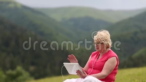 金发女人坐在草地上的草地上在Skype上聊天视频的预览图