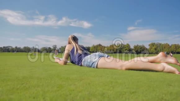 在公园里躺在草地上读一本书的年轻学生女孩的多利照片视频的预览图