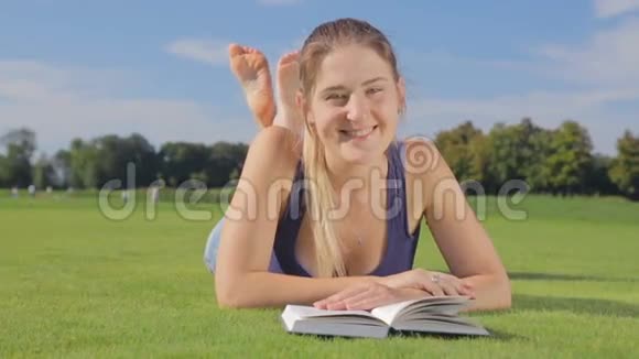 微笑的少女躺在草地上拿着书视频的预览图
