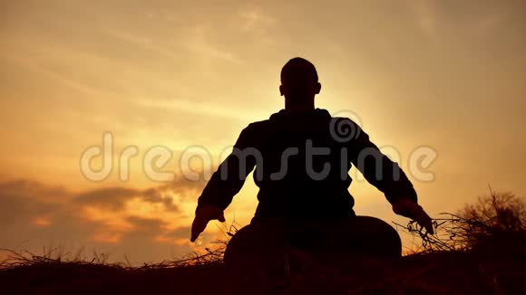 一位在日落生活方式阳光下冥想的男僧的剪影佛教在日落时祈祷健康的方法视频的预览图