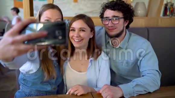 三个朋友坐在咖啡馆里玩得开心交流自拍视频的预览图