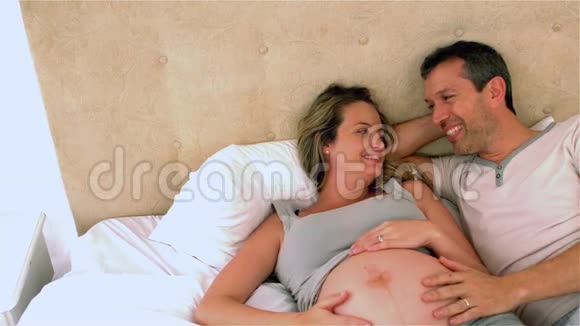 幸福的未来父母在床上聊天摸着肚子视频的预览图