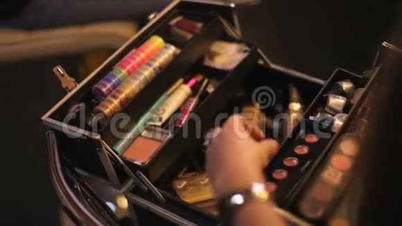 化妆师从她的手提箱里拿出化妆品专业化妆品化妆师在行李箱里多元色视频的预览图