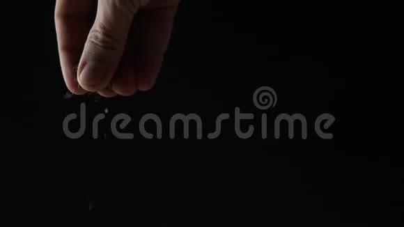 男人在黑暗的背景下洒一些草药超级慢动作视频的预览图