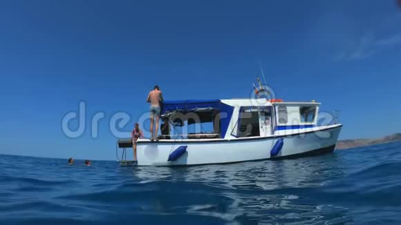 英俊的年轻人从一艘船或游艇跳入大海或海洋暑假和朋友一起游客们玩得很开心视频的预览图