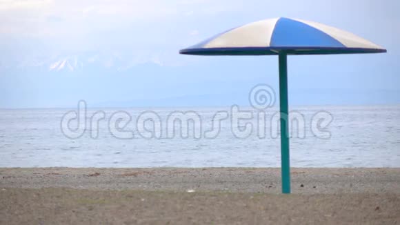 空的沙滩和蓝色的太阳伞迎着雪峰4K低季视频视频的预览图