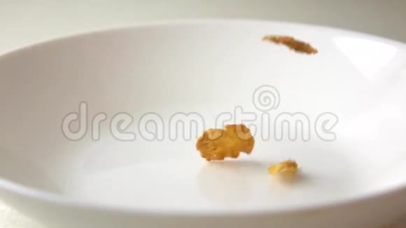 玉米片干果和葡萄干散在白色盘子上的慢速运动视频的预览图
