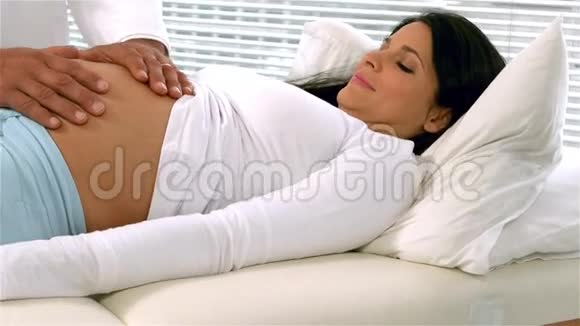 手放在孕妇肚子上的医生视频的预览图
