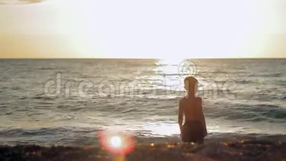 小男孩在日落时呆在平静的大海里视频的预览图