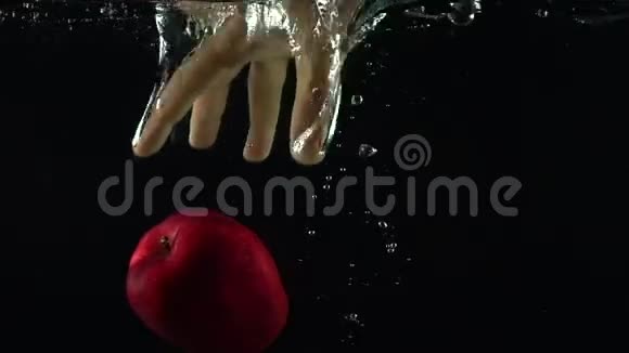 人手一伸抓住水中漂浮的红苹果超级慢镜头视频的预览图