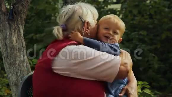 奶奶高兴地在花园里抱着小孙子视频的预览图
