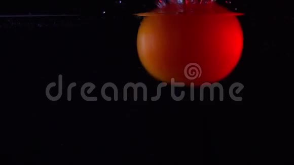 西红柿落水超级慢动作近景视频在黑暗背景下视频的预览图