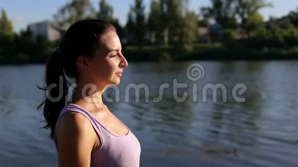 美丽的女孩在湖边做瑜伽特写视频的预览图