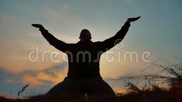 一位在日落阳光下冥想的男僧的剪影佛教在日落时祈祷健康的生活方式视频的预览图