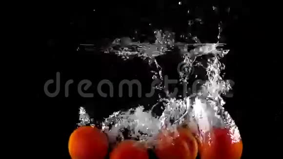 西红柿在水中落下和漂浮的慢镜头黑色背景视频的预览图
