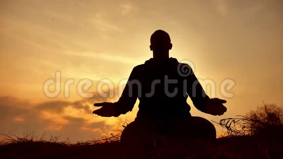 一位在日落阳光下冥想的男僧的剪影佛教生活方式在日落时分祈祷健康的生活方式视频的预览图