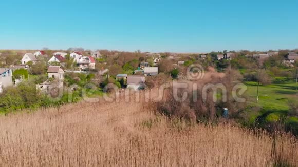 上午在池塘岸边山上鸟瞰乡村房屋视频的预览图