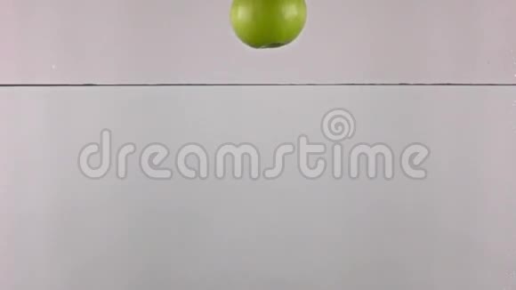 绿色苹果在灰色背景下在水中落下动作非常慢视频的预览图