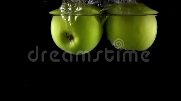 两个绿苹果在黑色背景下倒在水中速度非常慢视频的预览图