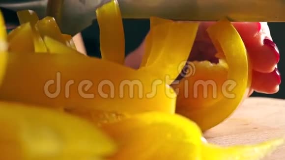 年轻女子用红色指甲油切黄甜椒宏观镜头视频的预览图