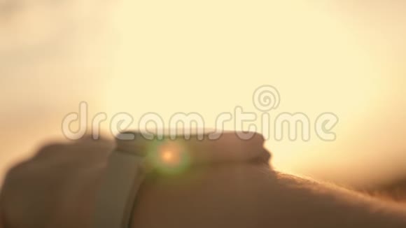 日落时一个在田野里的女孩看着一个智能时钟傍晚在日落时分用智能跑步视频的预览图