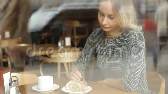 女人在咖啡馆里吃美味的蛋糕喝咖啡视频的预览图