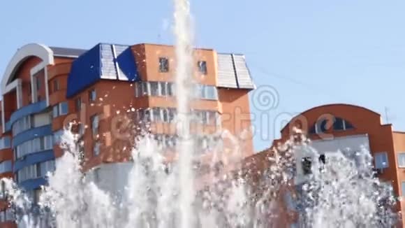 阳光明媚的一天城市建筑背景上的喷泉流慢动作视频的预览图