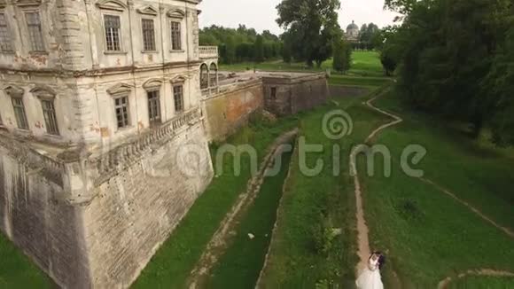 一对美丽的年轻夫妇站在城堡的空中景色4k视频的预览图