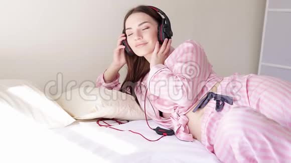 床上穿着睡衣的女人从耳机里随着音乐起舞视频的预览图