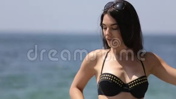 穿着黑色比基尼的黑发美女站在海边的悬崖边摆姿势视频的预览图