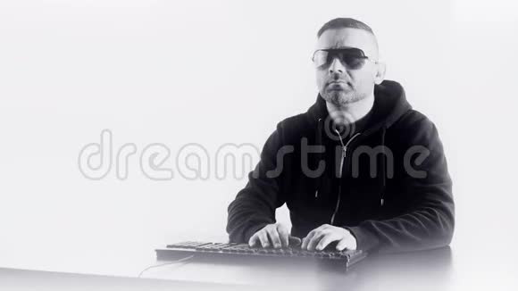戴太阳镜的人在电脑键盘上打字白色复印空间视频的预览图