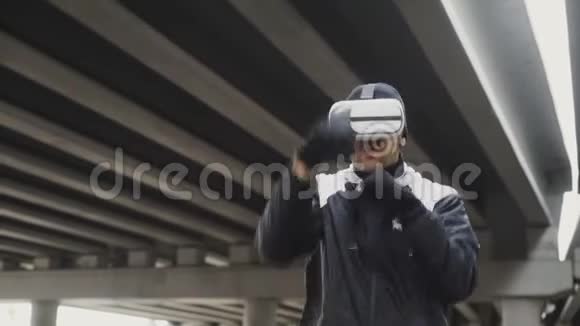 青年拳击手在VR360耳机训练拳打脚踢的虚拟现实在城市的位置户外冬季视频的预览图