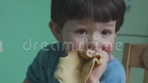 可爱的小男孩吃带有奶油和果酱的煎饼视频的预览图