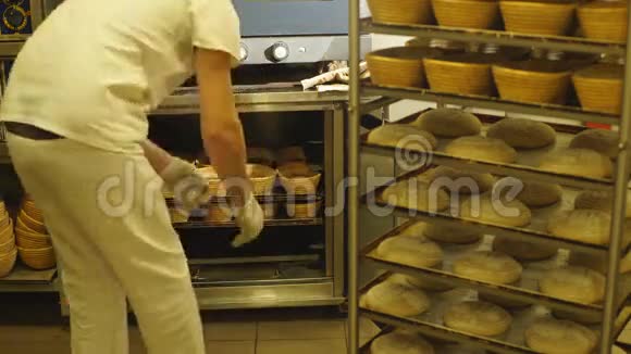 贝克在一家现代化的面包店里从烤箱里拿出一条刚烤好的面包视频的预览图