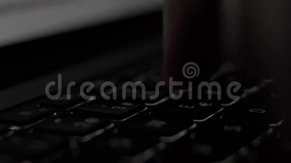 侧用笔记本电脑背光键盘在黑暗的房间里合上男性手打字视频的预览图